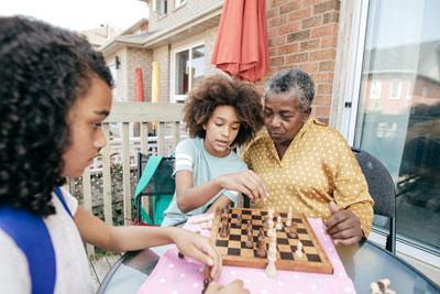Elderly woman and children playing chess.