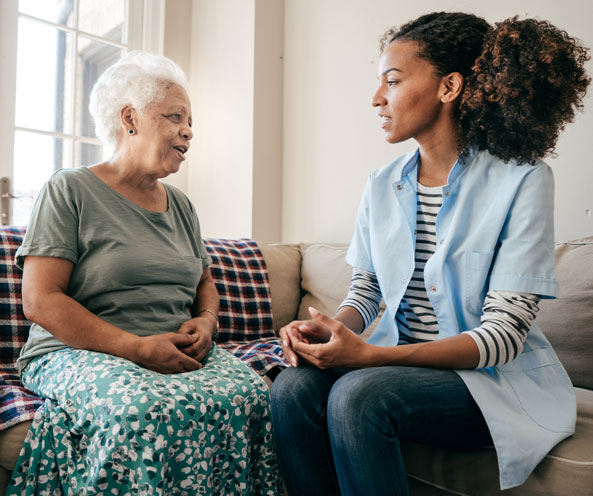 Caregiver and patient sitting in a couch and talking.